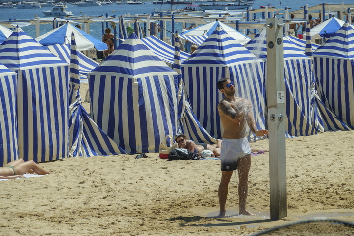 Un hombre se refresca con la ducha en una playa de Donostia.