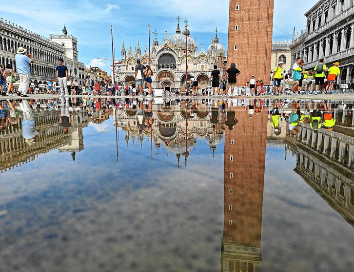 En la página anterior, Piazza San Marco, donde los auxiliares turísticos piden a los visitantes que no se sienten en el suelo. Sobre estas líneas, una góndola con turistas atraviesa un canal veneciano.