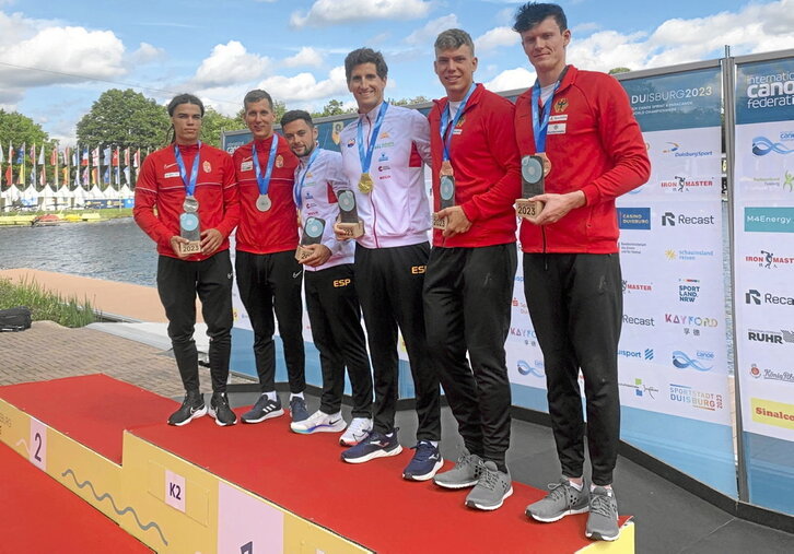 Iñigo Peña posa sonriente en el centro del podio con su medalla de oro junto a su compañero Pedro Vázquez.