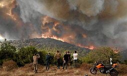 Varias personas observan y fotografían cómo el incendio arrasa un bosque en Sikorahi, cerca de Alexandroupoli, en Evros.
