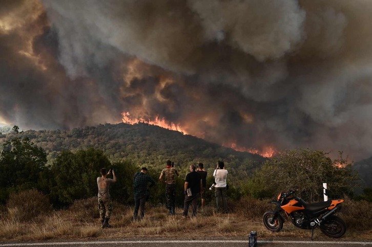 Varias personas observan y fotografían cómo el incendio arrasa un bosque en Sikorahi, cerca de Alexandroupoli, en Evros. 