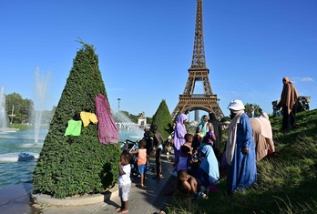 Personas de todas las edades se refrescan en las fuentes aledañas a la Torre Eiffel.