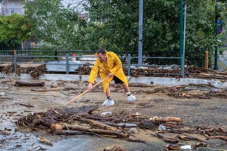 Gizon bat euriteek utzitako zaborra garbitzen Volosen, astearte honetan.