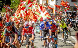 Los ciclistas pasan por debajo de un mar de banderas de Nafarroa e ikurriñas.