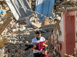 Un hombre lleva el cuerpo de un niño entre los escombros de una casa en Tafeghaghte.