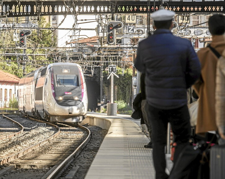 Un controlador y varios pasajeros aguardan a la entrada de un TGV en la estación de tren   de Baiona.