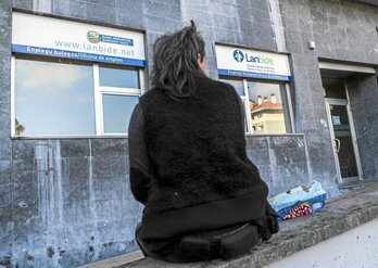 Una mujer aguarda sentada ante una oficina de Lanbide.