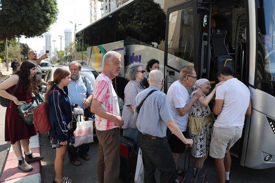 Varios residentes hacen cola para montar a un autobús que los transportará a un hotel en Tel Aviv.