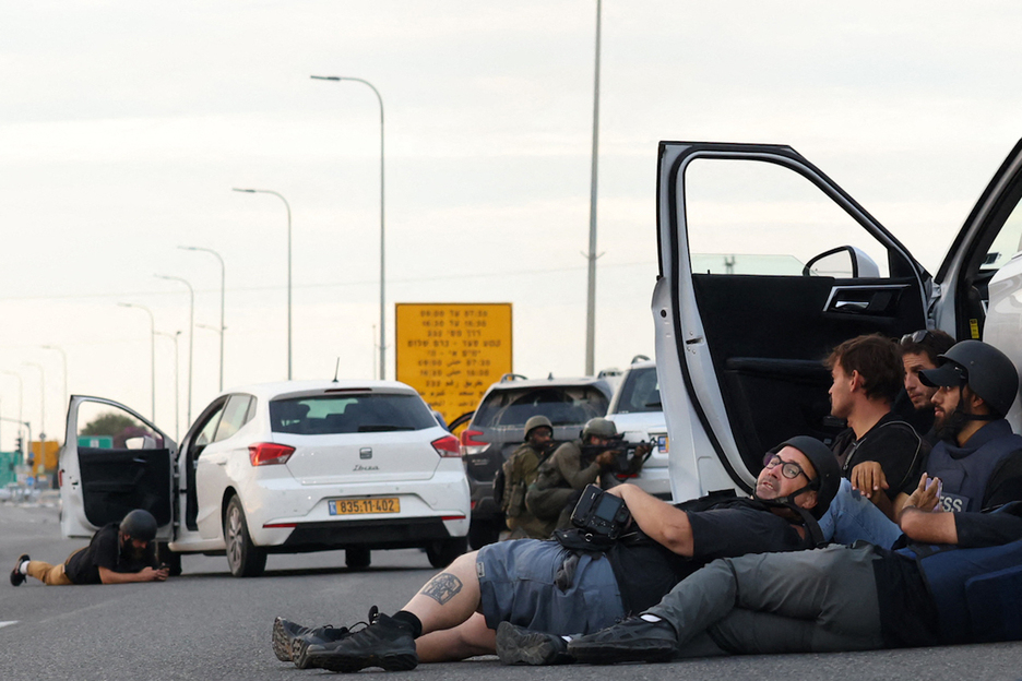 Periodistas se refugian detrás de los coches mientras los soldados israelíes toman posiciones durante los enfrentamientos con los combatientes palestinos cerca.
