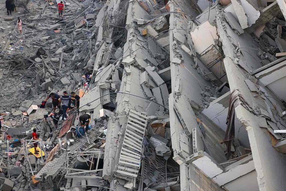 Gazatíes examinan un edificio en ruinas tras ser bombardeado.