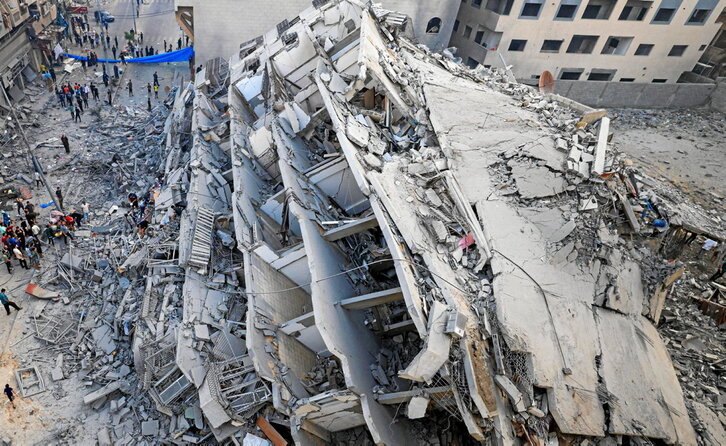 Varios palestinos inspeccionan las ruinas de un edificio destruido por los bombardeos israelíes en Gaza.