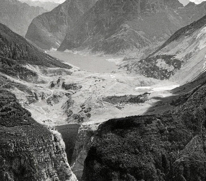La presa del Vajont después del derrumbe de 260 millones de metros cúbicos. A la derecha, el campanario de Longarone y la presa tras el desastre.