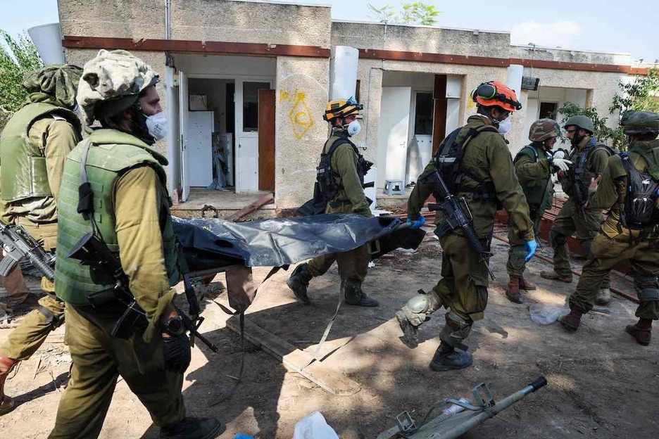 Soldados israelíes retiran el cadáver de un compañero muerto durante un ataque de militantes palestinos en Kfar Aza, al sur de Israel, en la frontera con la Franja de Gaza.