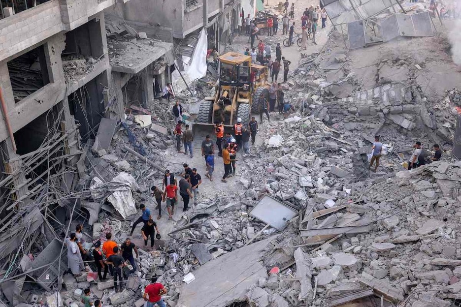 Civiles palestinos y equipos de rescate ayudan a retirar los escombros del centro de la ciudad de Jan Yunis, fuertemente bombardeada tras los bombardeos israelíes de la noche anterior.