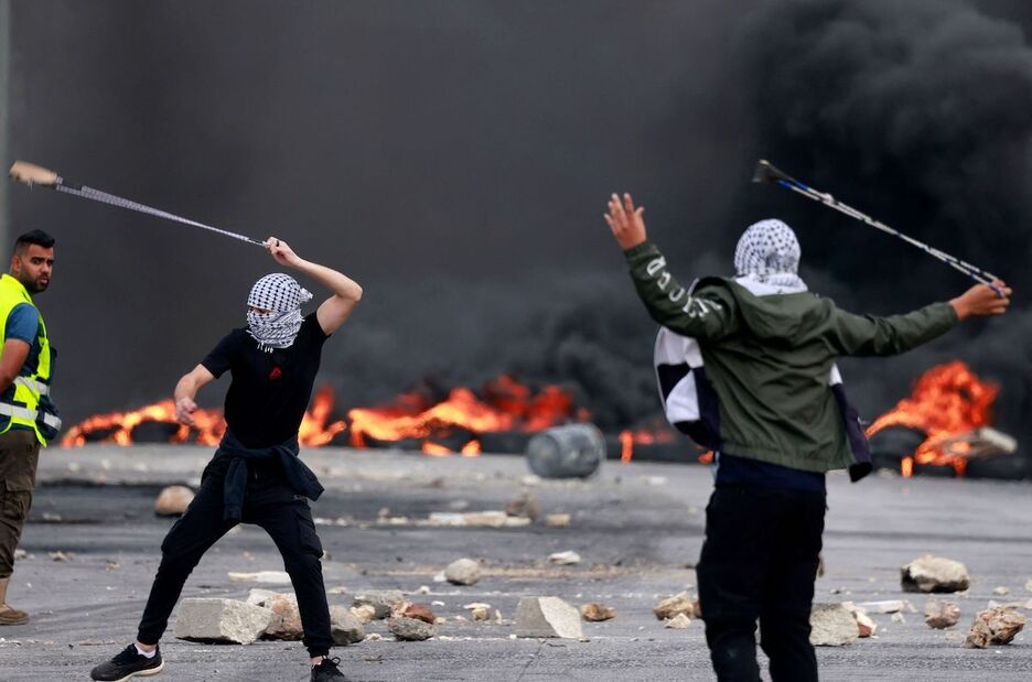 Palestinos lanzan piedras a las fuerzas israelíes durante una manifestación contra el bombardeo de la Franja de Gaza, en la ciudad de Ramala, en la Cisjordania ocupada.