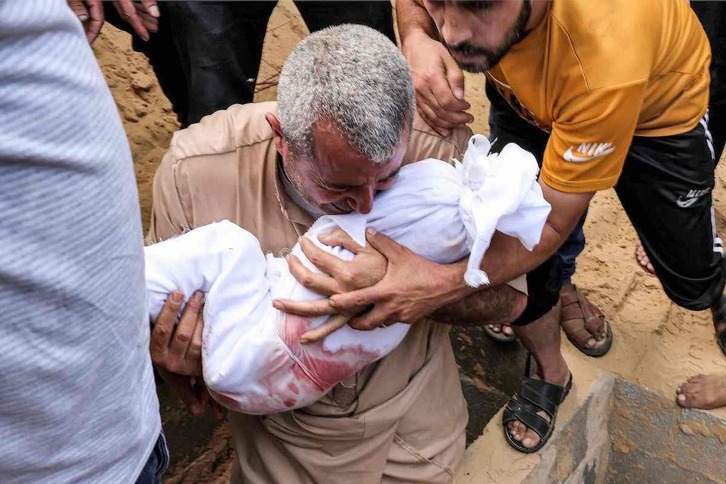 Un hombre sostiene a un bebé muerto en los bombardeos israelíes.