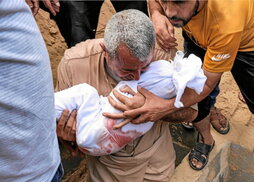 Un hombre sostiene a un bebé muerto en los bombardeos israelíes.