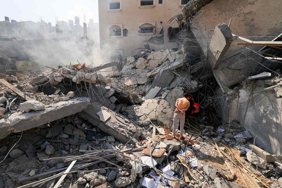 Palestinos buscan supervivientes bajo los escombros de un edificio derrumbado tras un ataque israelí en Jan Yunis.