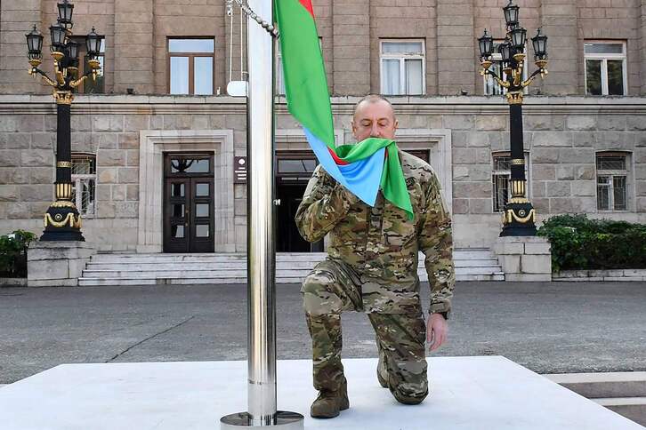 Azerbaijango Prentsa Bulegoak ateratako eta zabaldutako argazki honek Ilham Aliyev presidentea erakusten du belauniko Khankendin, Azerbaijango bandera nazional baten aurrean. 