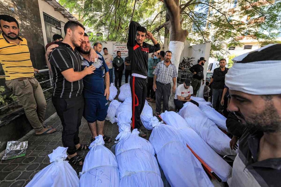 Palestinos se reúnen junto a los cuerpos cubiertos de las víctimas del ataque.
