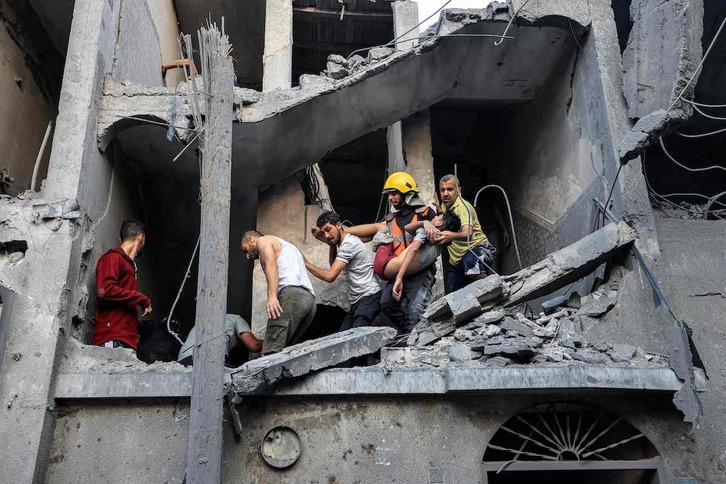Miembros de la defensa civil palestina llevan un niño muerto en el bombardeo de viviendas en Jan Yunis.