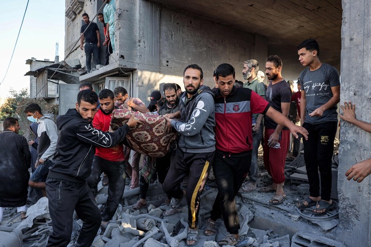 Palestinos recuperan el cadáver de una persona en un edificio bombardeado en Rafah.