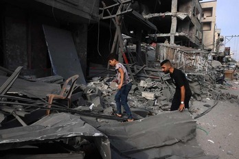 Palestinos buscando entre los restos de edificios bombardeados en Gaza.