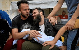 El padre de la familia Al Aqad llora mientras sostiene el cuerpo de su hijo muerto.