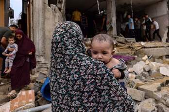 Una mujer sujeta a un bebé en brazos en una área bombardeada de Rafah, al sur de Gaza.