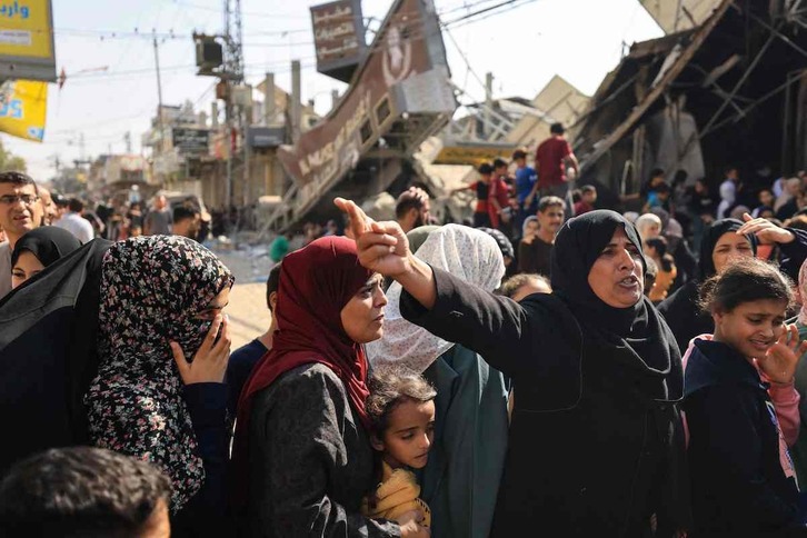 La gente hace cola para comprar pan frente a una panadería que fue parcialmente destruida en un ataque israelí en el campo de refugiados de Nuseirat, en el centro de la Franja.