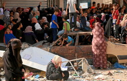 Palestinos hacen cola para comprar pan frente a una panadería parcialmente destruida en Nuseirat.