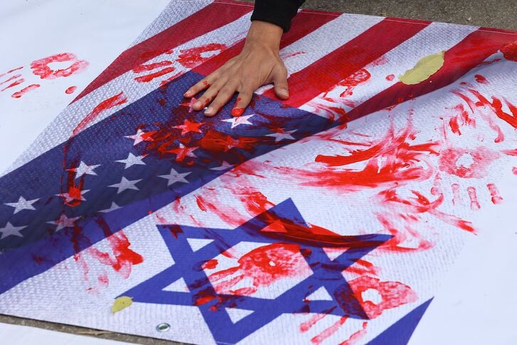Un participante en la protesta por la visita de Blinken a Ankara mancha las banderas de EEUU e Israel.