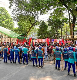Policías vigilan a los manifestantes, durante una protesta en Dacca.
