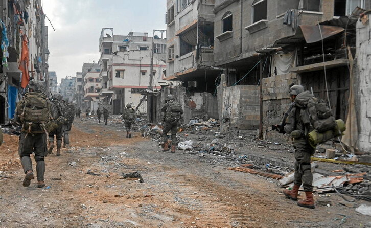 Soldados israelíes avanzan en una calle de la devastada ciudad de Gaza.