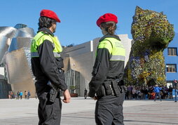 A la izquierda, foto de archivo de la Policía Municipal de Bilbo. Arriba, agentes de la Policía inglesa.