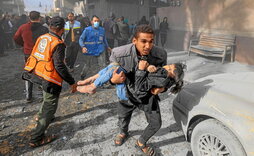 Un hombre lleva a una niña herida tras un ataque en Rafah.