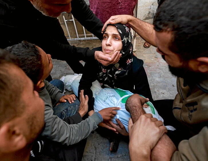 Una mujer, con el cadáver de su hija de cinco años en sus brazos, es reconfortada en Rafah.