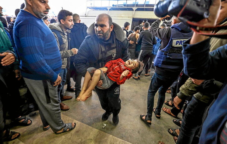 Un hombre lleva a una niña herida al hospital tras uno de los bombardeos en Jan Yunis.