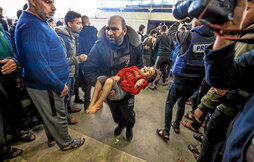 Un hombre lleva a una niña herida al hospital tras uno de los bombardeos en Jan Yunis.