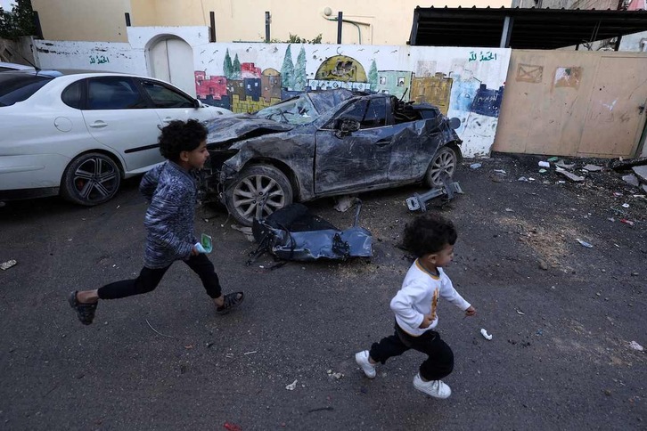 Dos niños corren ante unos coches dañados por un ataque israelí en el campo de refugiados de Jenin, en Cisjordania.