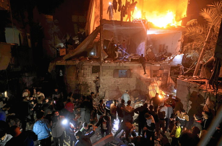 Palestinos buscan supervivientes entre los escombros de un edificio destruido.