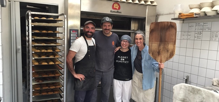 Cuatro de los seis miembros del equipo de Mendialdeko Ogia, frente al moderno horno de leña en el que elaboran sus productos de panadería y pastelería artesana. 