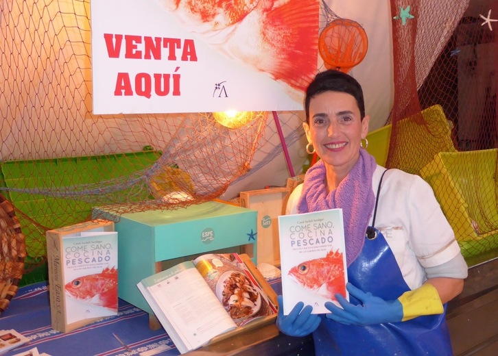 Carol Archeli sostiene un ejemplar de su libro, en la pescadería que regenta en el Mercado de la Bretxa.