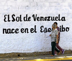 Dos mujeres caminan ante un mural que defiende la soberanía venezolana del Esequibo.