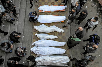 Palestinos permanecen junto a los cuerpos amortajados de familiares muertos a manos israelíes en Jan Yunis.