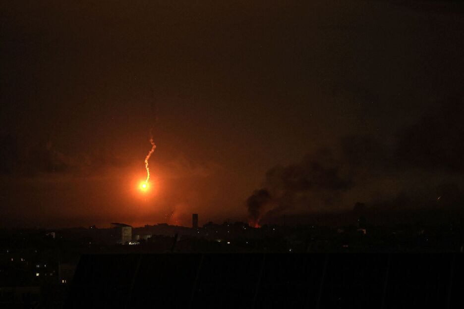 Una imagen tomada desde Rafah muestra una bengala iluminando el cielo mientras ondea humo tras el bombardeo israelí de Jan Yunis.