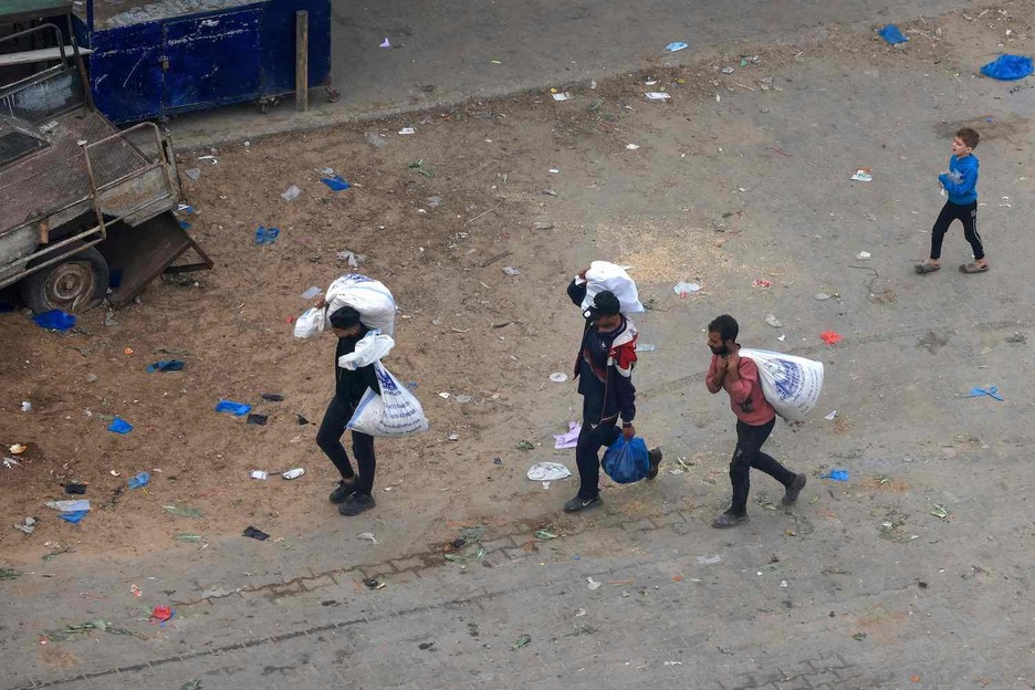 Palestinos transportan bolsas de alimentos en Rafah.