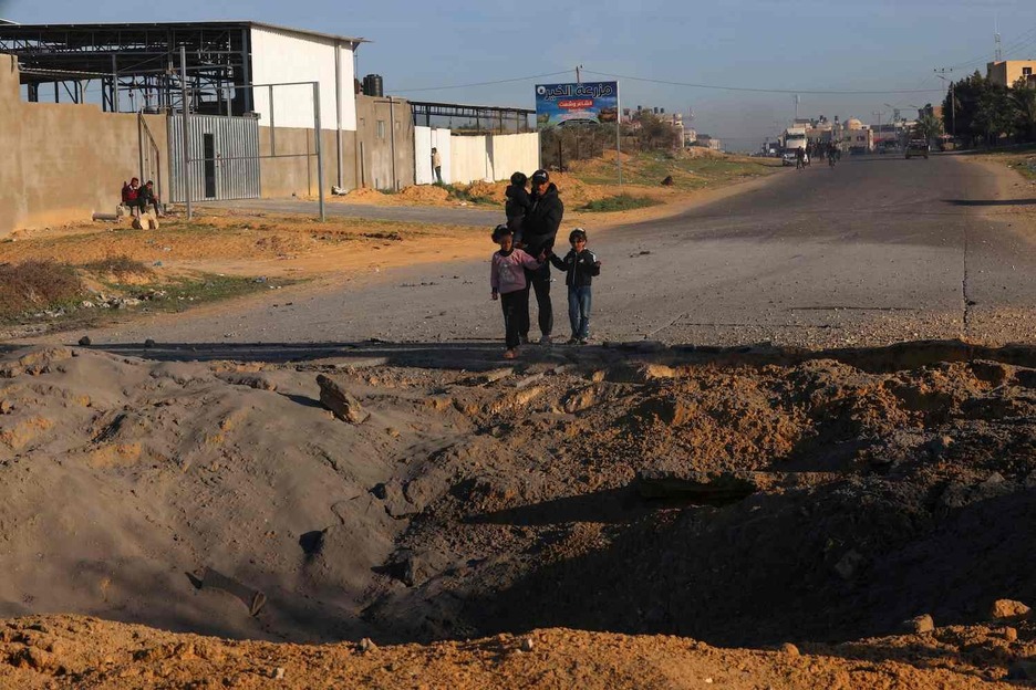 Palestinos que huyen de Jan Yunis hacia Rafah observan un cráter causado por los bombardeos israelíes en la carretera de Salah Al-Din.