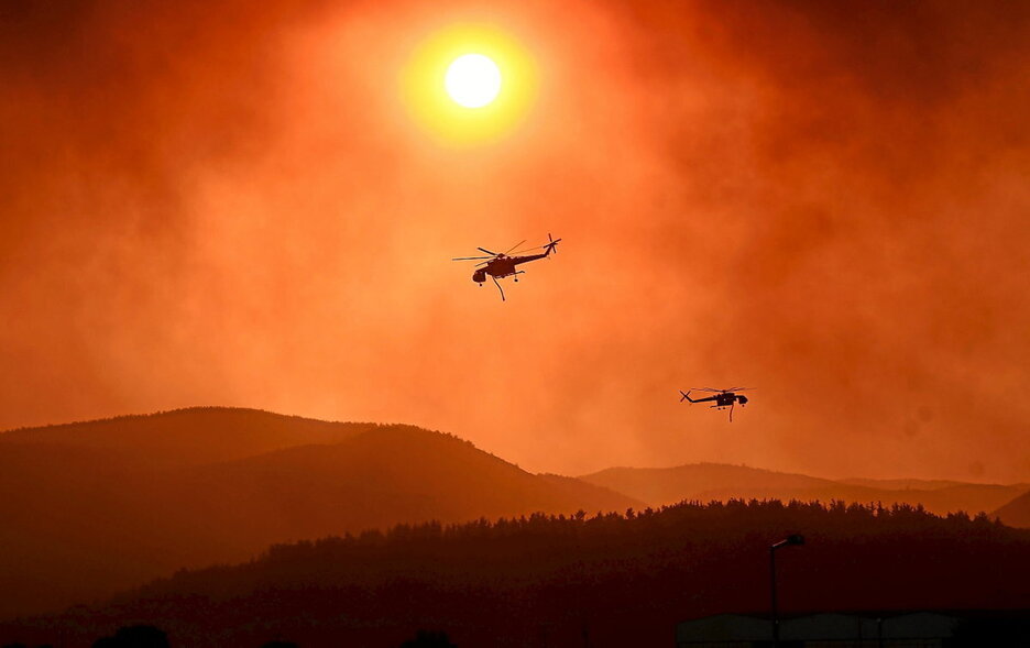 Helicópteros sobrevuelan un incendio en Grecia.