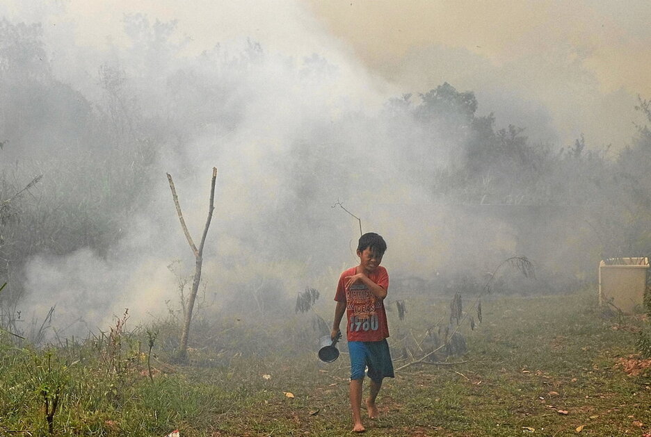 Un niño escapa del humo en el incendio de Ogan Ilir, Sumatra del Sur.